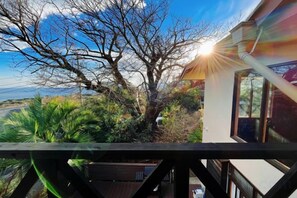 A balcony with a view of a tree and a distant landscape. - Vacation Rental Shirayuri (Ito)