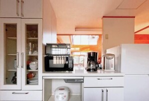 A compact kitchen with a microwave, coffee maker, and refrigerator. - Vacation Rental Shirayuri (Ito)