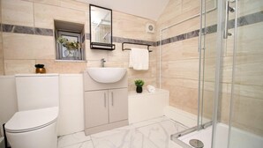 A modern bathroom with a toilet, sink, and shower. - 5 Bed House - Sleeps 16 - Parking - Wifi (Swansea)