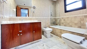 Un bagno moderno con un mobile bagno in legno, un water, un bidet, una vasca da bagno e un grande specchio.