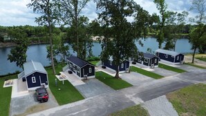 A row of small, dark blue cabins with a paved driveway and a grassy area in front. - Lake View Cabin, 20 miles from New Bern! (Maysville)