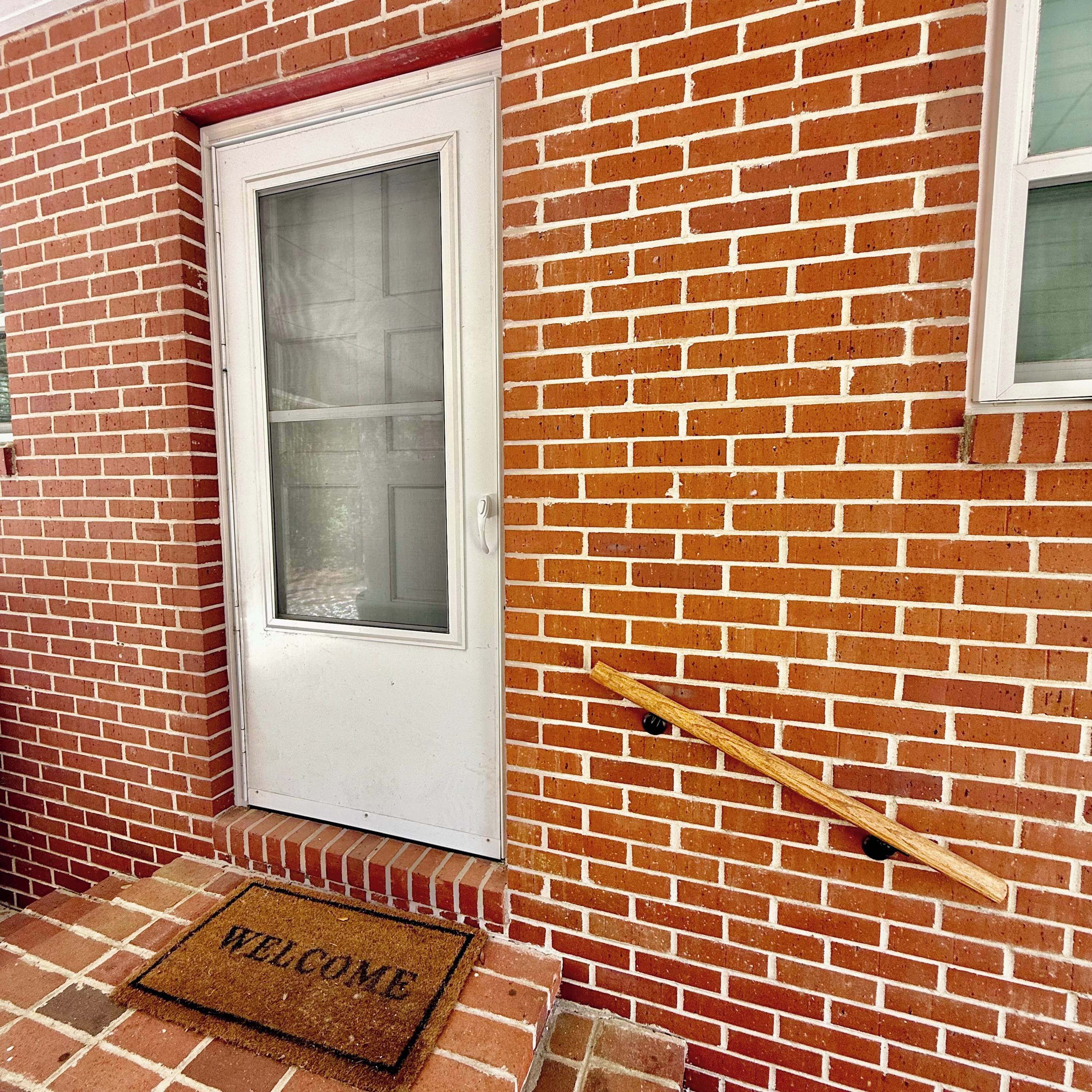 A red brick house with a white door and a window.