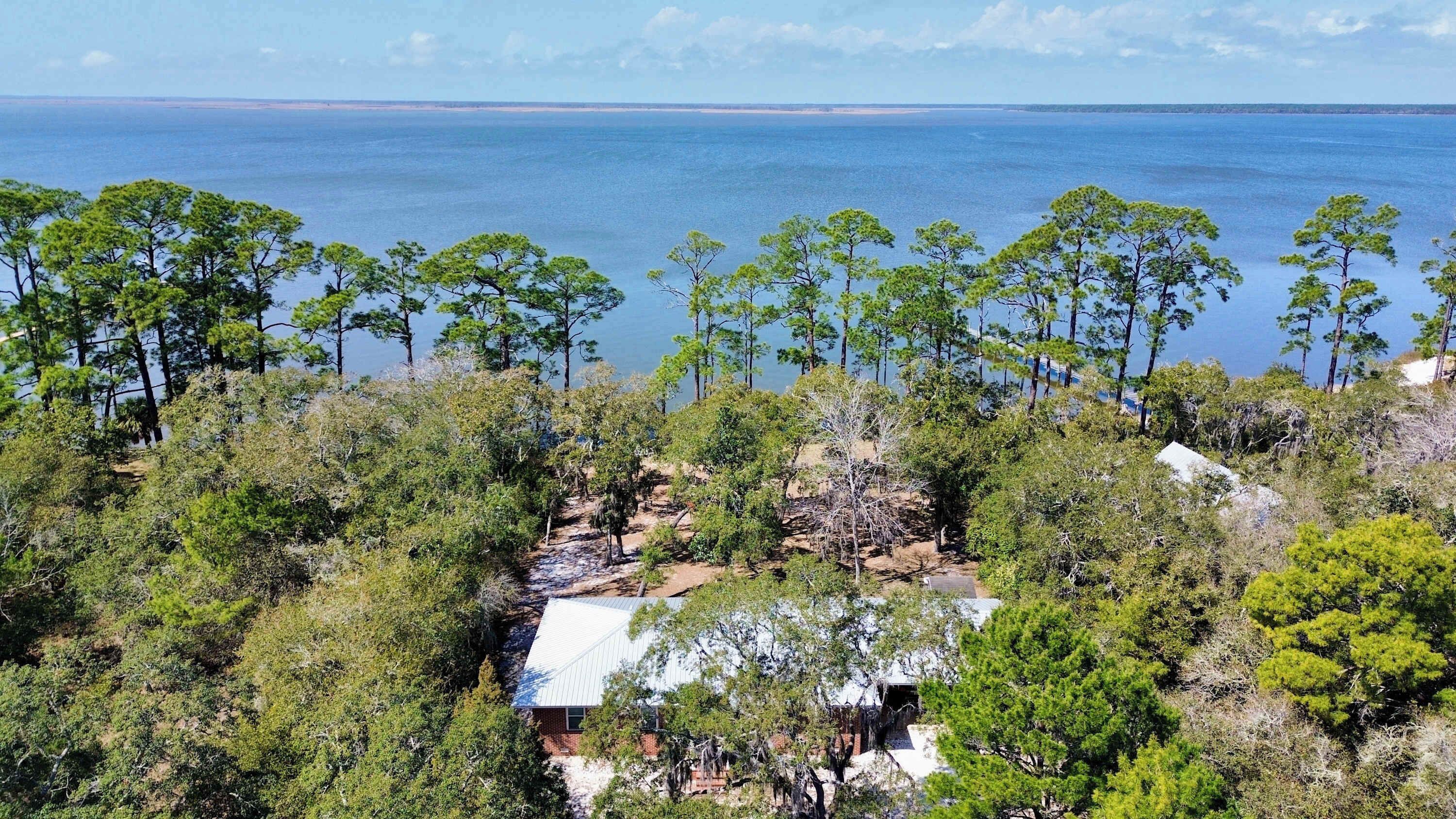 A coastal property with a view of the sea, surrounded by dense greenery and a few buildings.