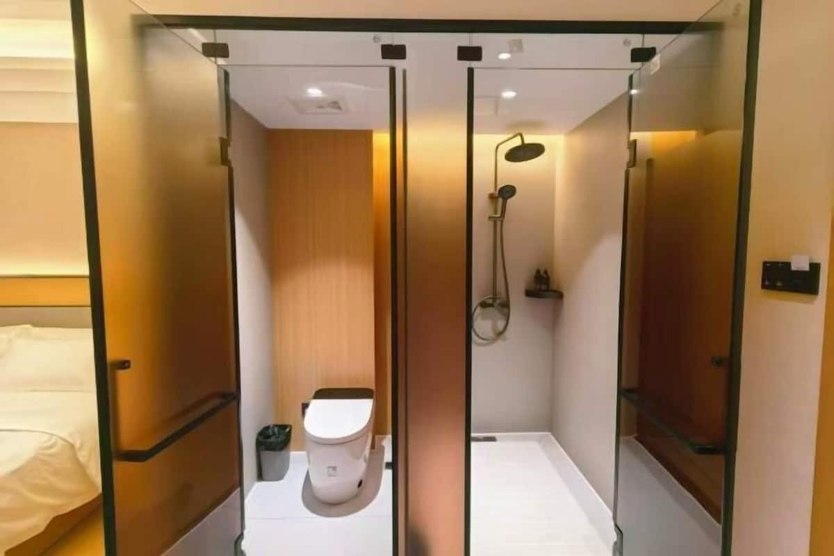 A compact, modern bathroom with a shower, toilet, and a small sink.
