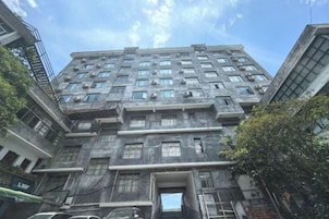 Un edificio de varios pisos con una entrada central, grandes ventanales y fachada plana.