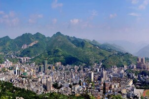 Un paisaje urbano con una zona densa y una cadena montañosa al fondo.