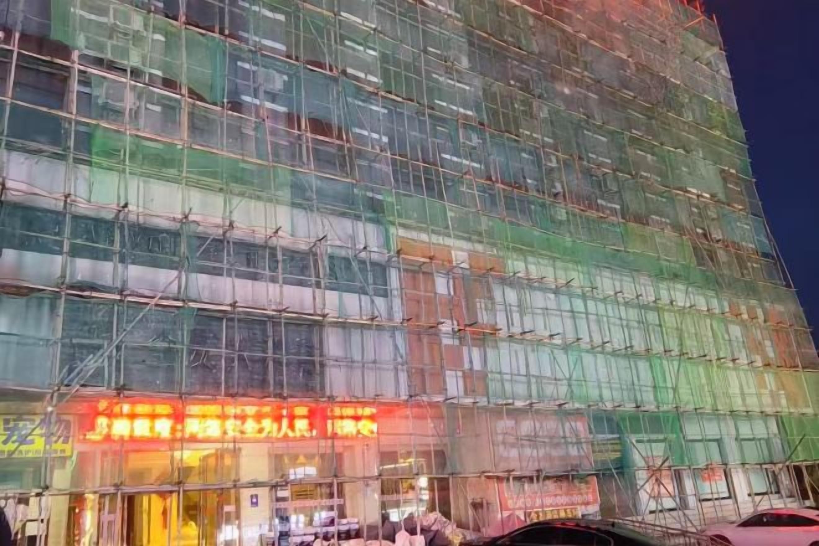 Un edificio de varios pisos con fachada de vidrio, rodeado de andamios, lo que indica construcción o renovación.