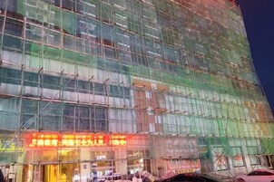 Un edificio de varios pisos con fachada de vidrio, rodeado de andamios, lo que indica construcción o renovación.