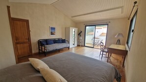 A bedroom with a large bed, a sofa, a desk, and a balcony with a table and chairs. - Rental House La Tranche-sur-Mer à La Grière - 50m from the beach - 14 people (La Tranche-sur-Mer)