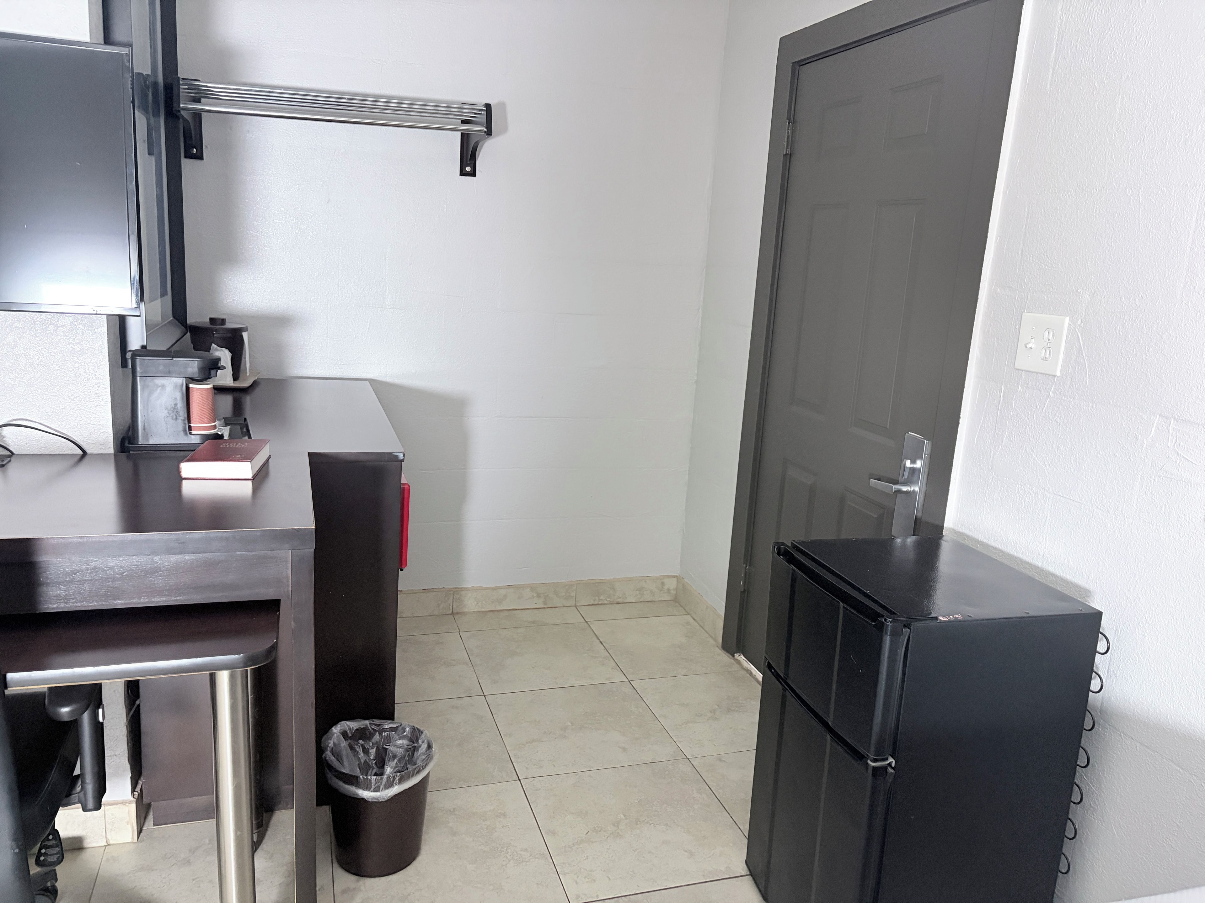 Una kitchenette compacta con cafetera, un cesto de basura y un refrigerador.