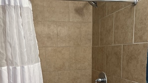 Zona de ducha con azulejos color beige, una cortina blanca y un pasamanos de metal.
