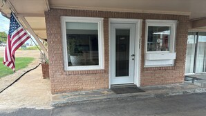 A two-story building with a brick facade, a front door, and a window with a sign that reads "OFFICE". - Budget Inn (Nocona)