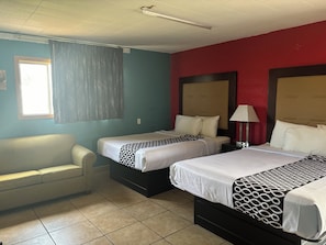 A hotel room with two beds, a sofa, and a window with curtains. - Budget Inn (Nocona)
