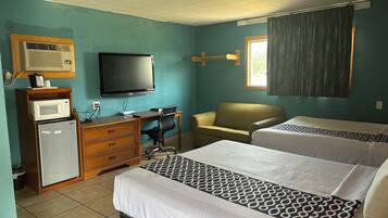 A hotel room with two beds, a desk with a chair, a television, a microwave, and a refrigerator.