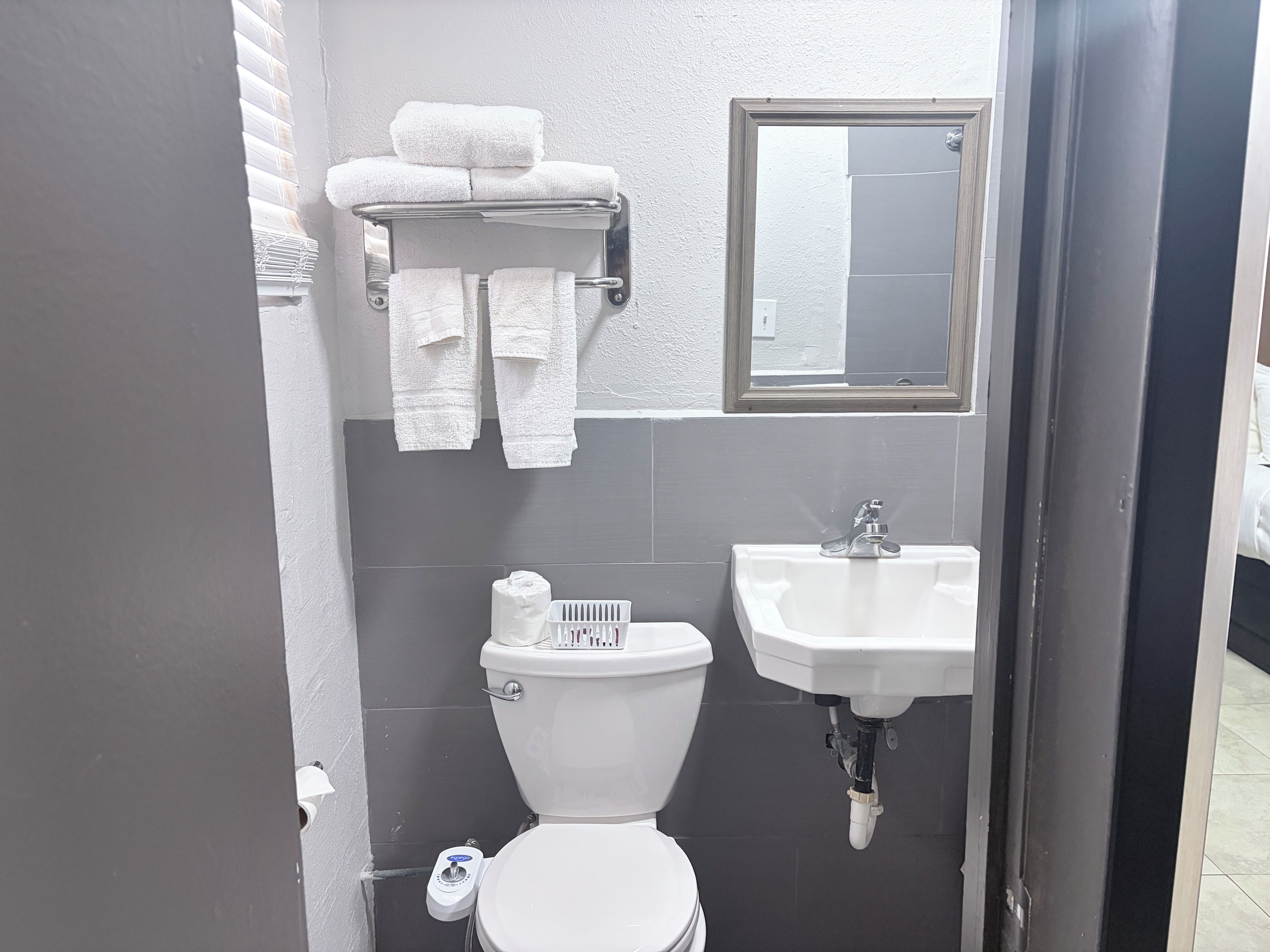 A bathroom with a toilet, sink, towel rack, and a mirror.