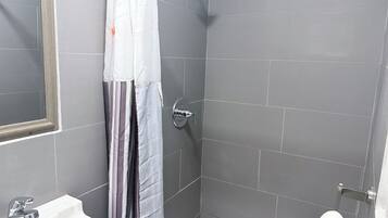 A bathroom with a shower, a sink, and a toilet.