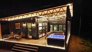 A modern outdoor lounge area with a hot tub, seating, and a sign reading "SHACK". - Pepper Jack Shack: Your Cozy Mountain Retreat (Newport)