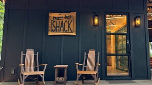 A wooden exterior wall with a sign reading "Pepper Jack Shack" and two rocking chairs in front. - Pepper Jack Shack: Your Cozy Mountain Retreat (Newport)