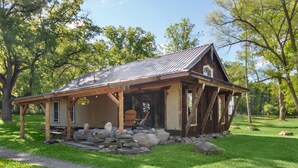 A rustic cabin with a sloped roof, wooden exterior, and a stone foundation.