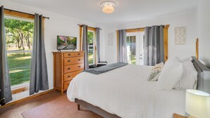 A bedroom with a large bed, wooden dresser, and a television on a stand.