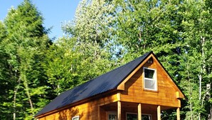 A wooden cabin with a porch, a front door, and a small set of stairs leading up to the entrance. - Bear Cabin: Charming 2-bedroom cabin with WiFi, AC in marvelous Sebec (Sebec)