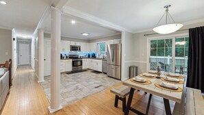 A modern kitchen with white cabinetry, stainless steel appliances, and a dining area with a wooden table set for six. - Durham 4BR/3BA: Game Room, Pool, Art! Sleeps 10 (Durham)