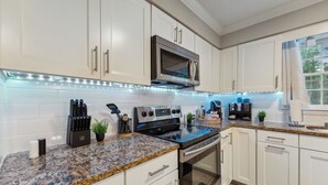A modern kitchen with white cabinets, a granite countertop, stainless steel appliances, and under-cabinet lighting. - Durham 4BR/3BA: Game Room, Pool, Art! Sleeps 10 (Durham)
