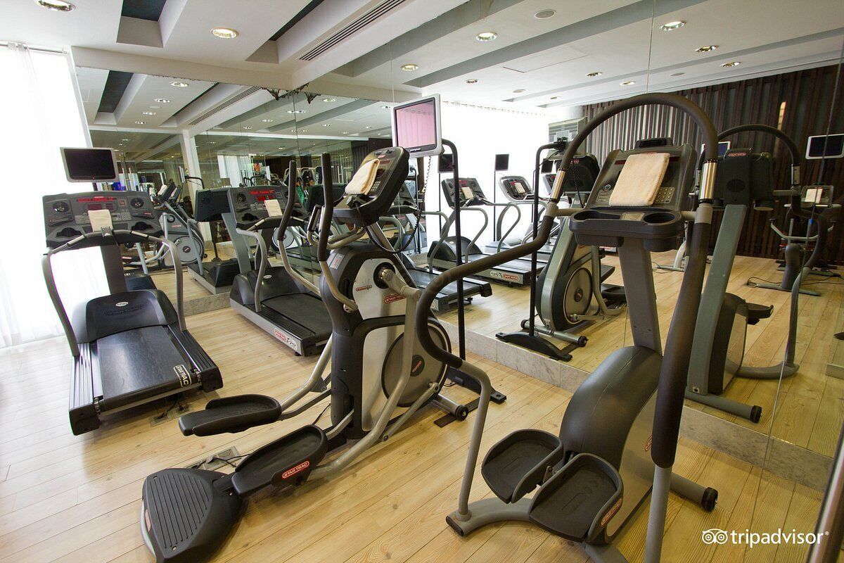 A gym with various cardio machines, including treadmills and elliptical trainers, arranged in a spacious layout.