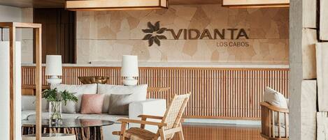 A modern lobby with a reception desk, wooden paneling, and a sofa with cushions.
