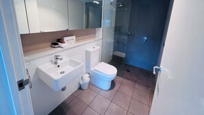 A modern bathroom with a glass shower enclosure, a white sink, and a toilet. - One Bedroom Apartment (Hamilton)