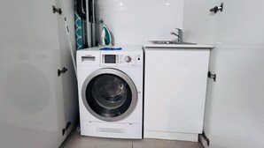A compact laundry room with a Bosch washing machine and a small sink. - One Bedroom Apartment (Hamilton)