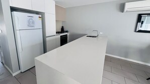 Eine moderne Küche mit weißen Schränken, einem eingebauten Backofen und einer Edelstahl-Spüle.