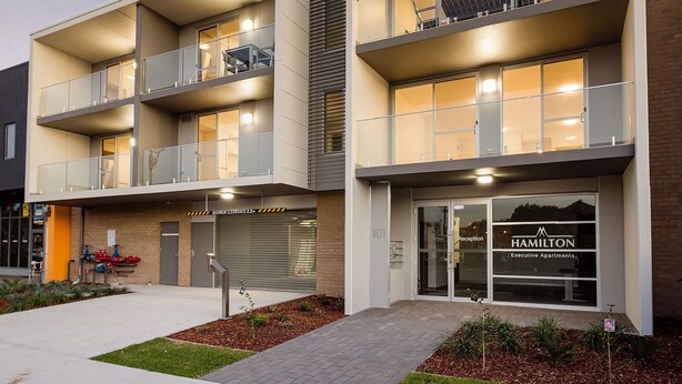 A modern apartment building with multiple balconies, a reception area, and a garage. - Two Bedroom Apartment (Hamilton)