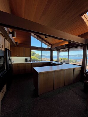 A modern kitchen with wooden cabinets, a large island, and a view of the ocean. - Spacious 2 bedroom home with 2 bedroom cabin on the water at Hood Canal. (Belfair)