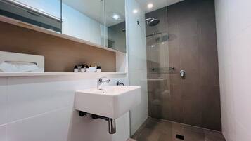 A modern bathroom with a white sink, a glass shower enclosure, and a mirror above the sink.