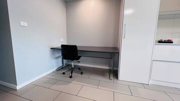 A modern office space with a desk, chair, and white cabinets.