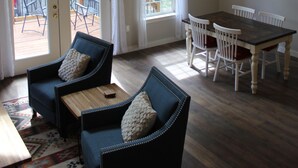 En rummelig stue med højt til loftet, et spisebord med stole, en sofa og en loftvifte.