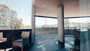 An outdoor patio area with seating and a view of trees and a distant landscape. - Three Bedroom Cockatoo Lodge (Valentine)