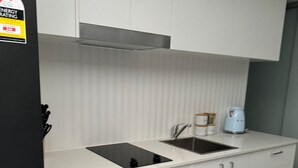 Una cucina moderna con mobili bianchi, un frigorifero nero, forno integrato e microonde.