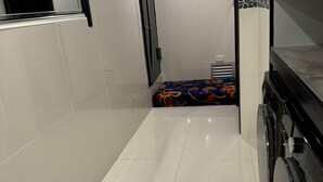 Un corridoio stretto con pavimenti e pareti piastrellati di bianco, che conduce a una stanza con un tappeto colorato e decorato.