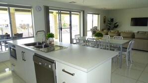 A modern kitchen with a dishwasher, a sink, and a dining area with a table and chairs. - Marina Belle, Wallaroo (Wallaroo)