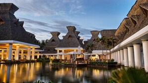 Resort com piscina, estruturas de telhado de palha e um céu noturno tranquilo.