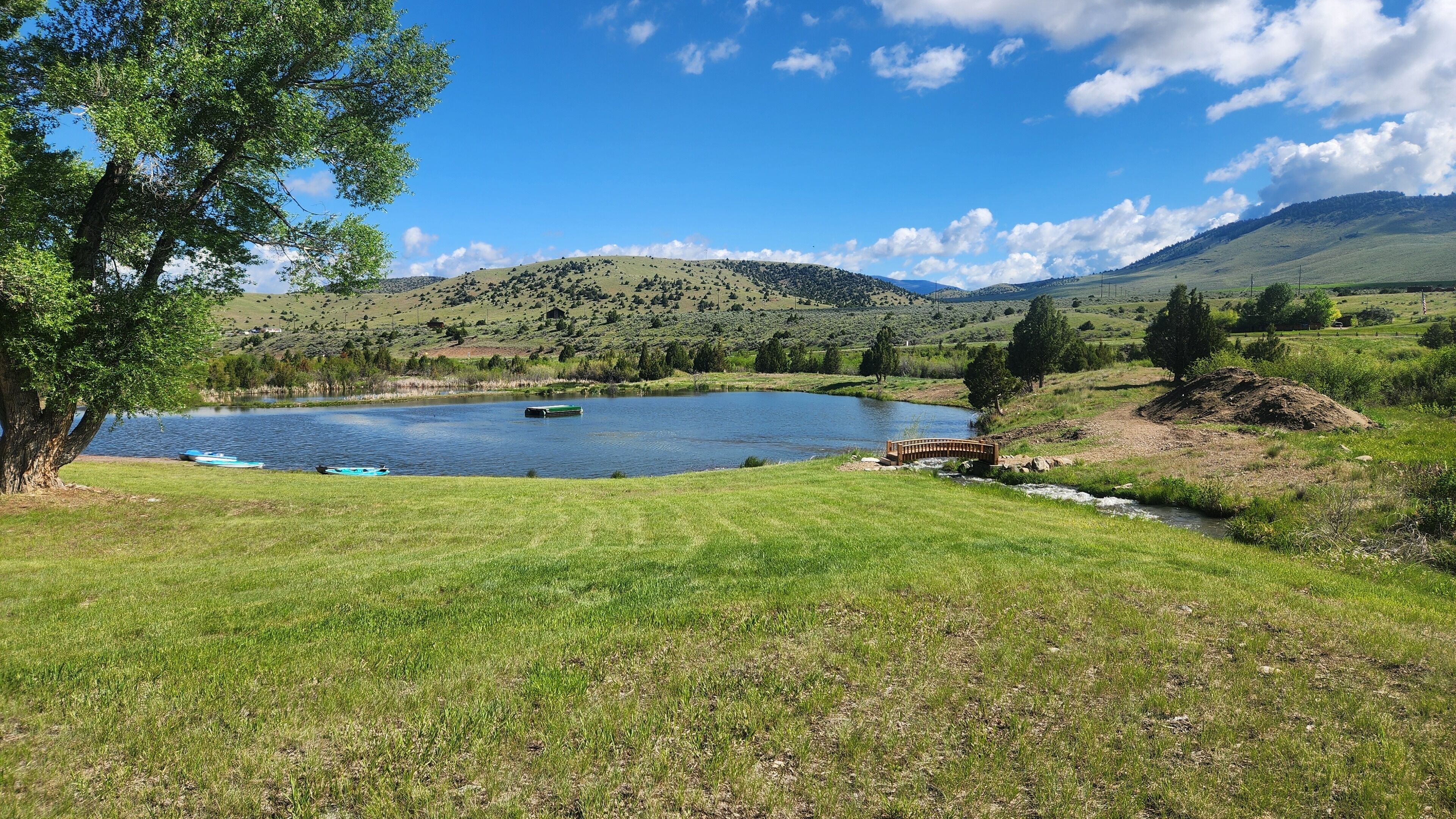 Un paisaje sereno con un lago, campos cubiertos de pasto y un puente.