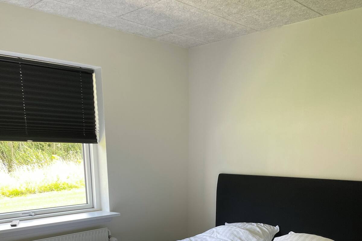 A single bed with a black headboard in a room with a window and radiator.