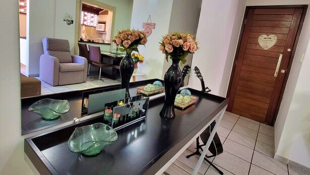Eine moderne Küche mit schwarzem Arbeitsplatz, zwei Vasen mit Blumen und einer Holztür mit Herzverzierung.