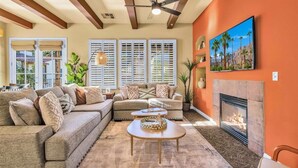 A living room with a sectional sofa, a coffee table, a fireplace, and a ceiling fan. - Perfectly Located Charming Villa Near Main Pool #A (La Quinta)