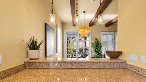 A kitchen with granite countertops, wooden cabinets, and pendant lighting. - Perfectly Located Charming Villa Near Main Pool #A (La Quinta)