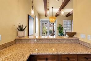 Kitchen features a granite countertop, wooden cabinets, and pendant lights.