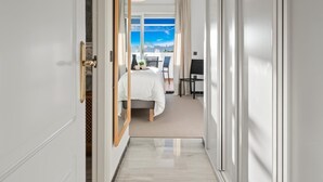 A hotel corridor with a bed, a desk, and a view of the city.