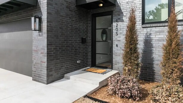 Un bâtiment moderne avec une façade en briques, une porte d’entrée en verre et une boîte aux lettres.
